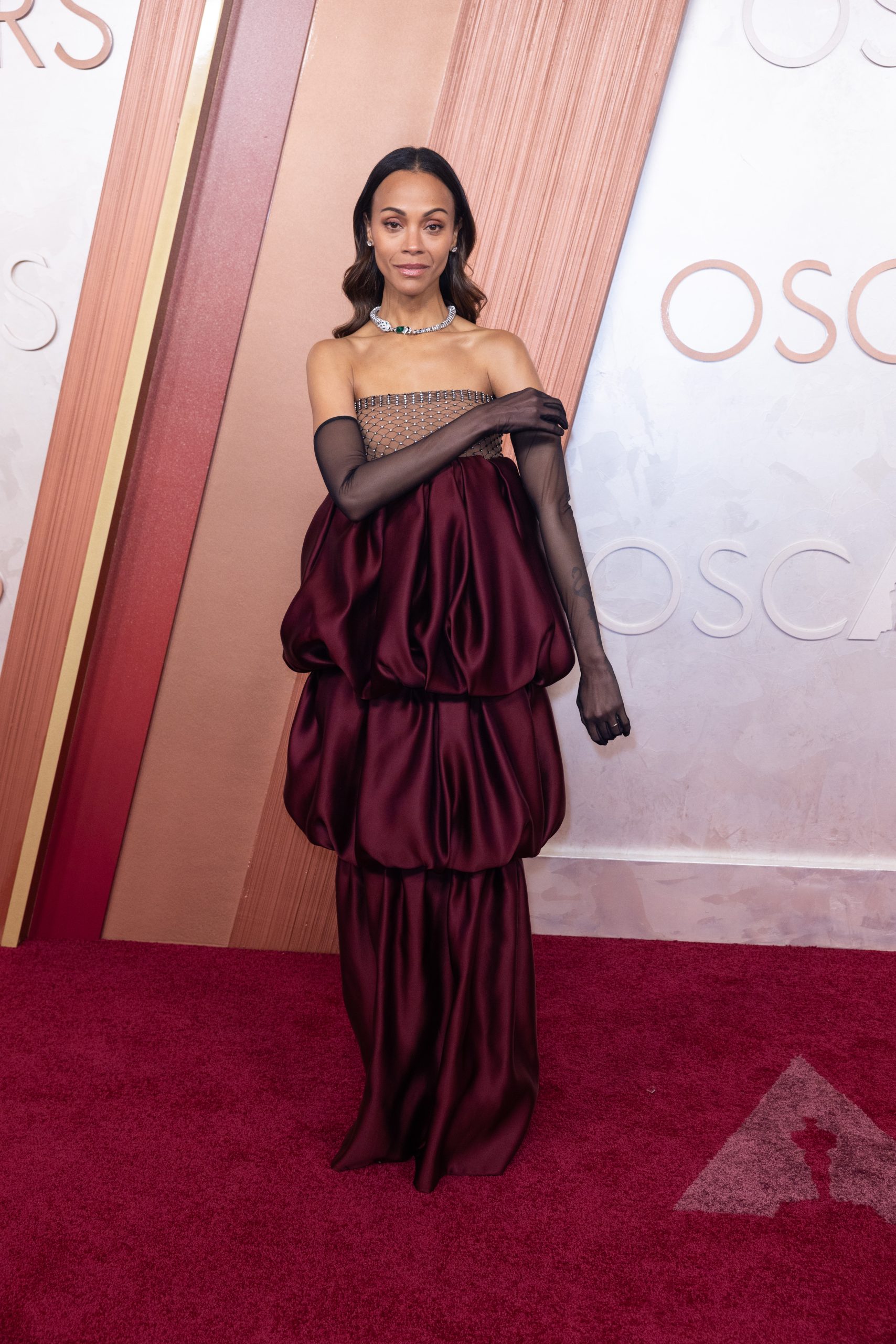 Emilia Perez actress Zoe Saldaña wore a gorgeous Saint Laurent look at this year’s awards. The maroon gown featured a rhinestone-adorned bodice and tiers of satin, creating an eye-catching silhouette. She finished off the look with sheer opera gloves.